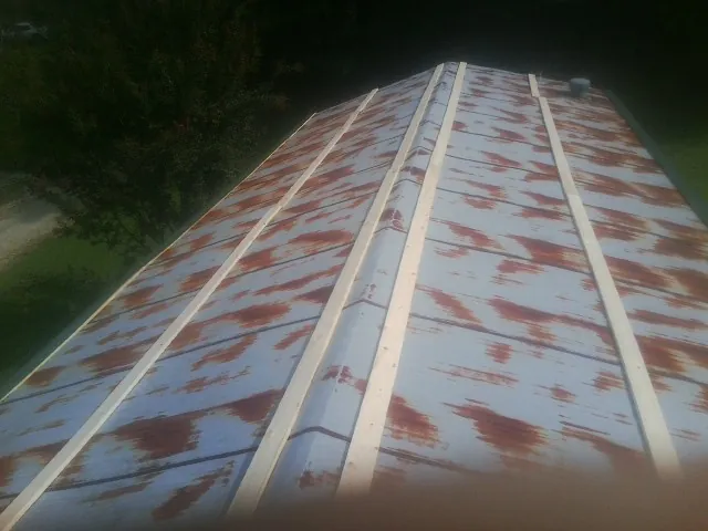 Rusted metal roof panels with new wood purlins before replacement — Storm Damage Roof Repair in Worthington Springs by Roofing Brothers