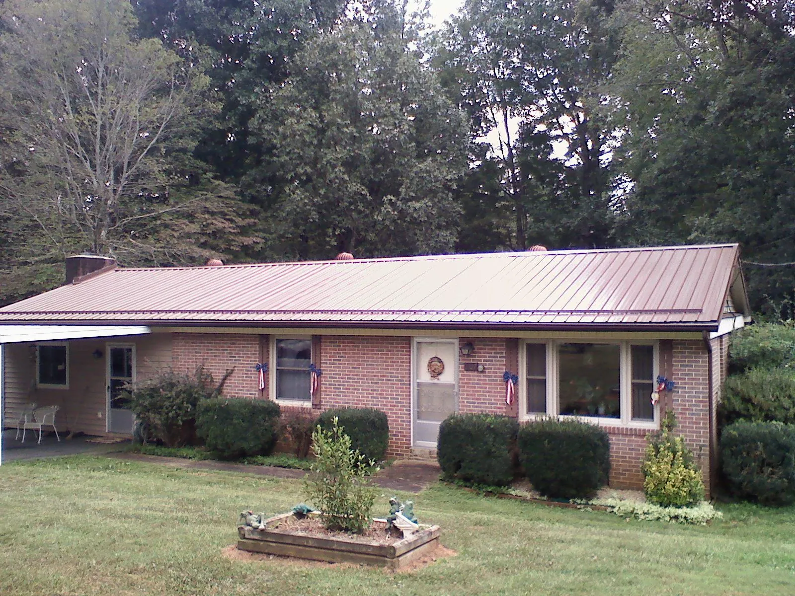 Bronze metal roof on a brick ranch home with a carport in Worthington Springs
