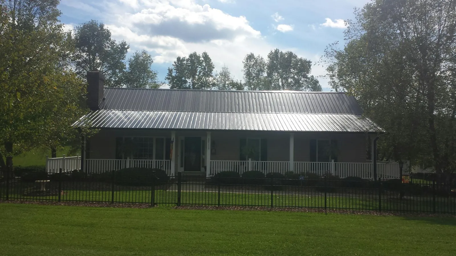Gray metal roof on a brick ranch with a full width front porch — Gutter Guard Installation work by our crew in Worthington Springs