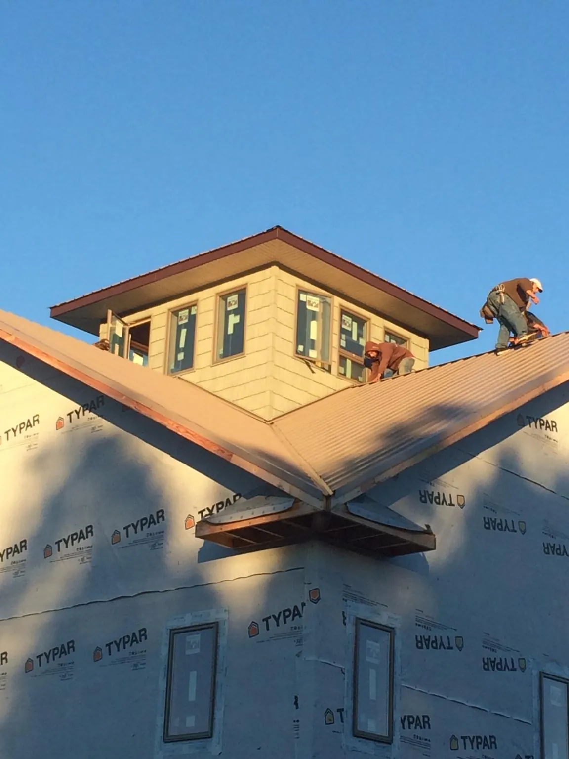 Roofers working around a rooftop cupola on a new metal roof at sunset — Roof Waterproofing in Worthington Springs by Roofing Brothers